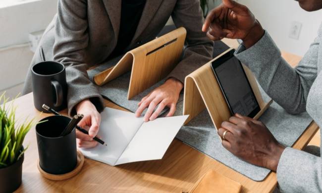 Freelancer mit iPads, die in ein Heft schreiben.