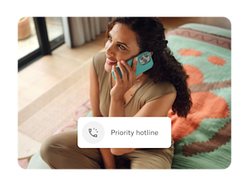 A smiling woman sits indoors talking on a phone, with a "Priority hotline" icon overlaid on the image.