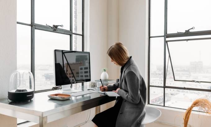 Una donna libera professionista che lavora in un appartamento luminoso con un computer e un notebook.