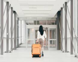 eine Frau zu Fuß mit einem Koffer im Flughafen.