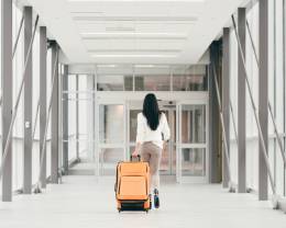 a woman walking with a suitcase in the airport.