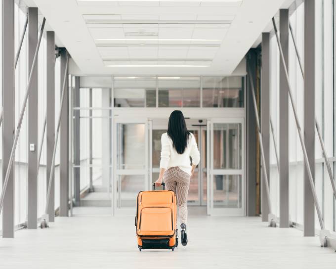 una donna a piedi con una valigia in aeroporto.