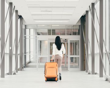 una donna a piedi con una valigia in aeroporto.