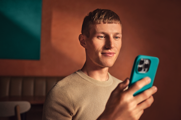 Un hombre mirando su teléfono móvil y sonriendo.