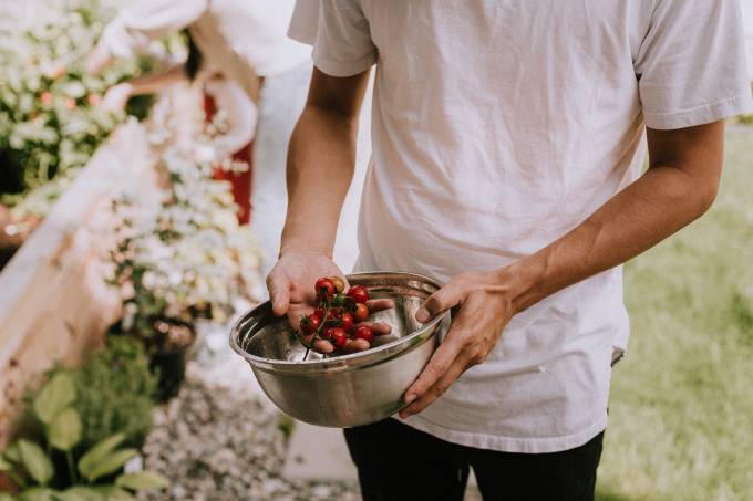 Une personne tient des tomates au-dessus d’un bol en métal.