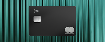 Una carta N26 Metal nero opaco con chip argentato e logo Mastercard minimalista su uno sfondo color teal testurizzato.