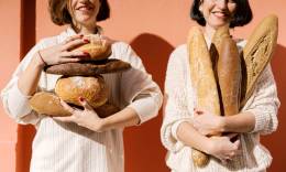 Two women holding bread.