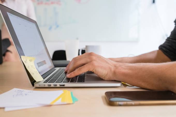 man typing on a laptop.