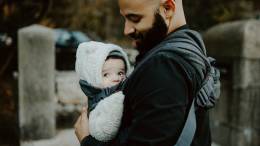 Homme barbu portant un bébé.