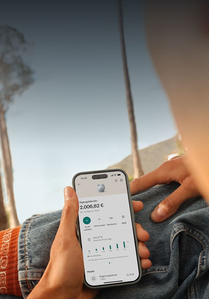 Eine Person auf dem Beifahrersitz eines Autos hält ein Smartphone in der Hand, auf dem eine Banking-App angezeigt wird.