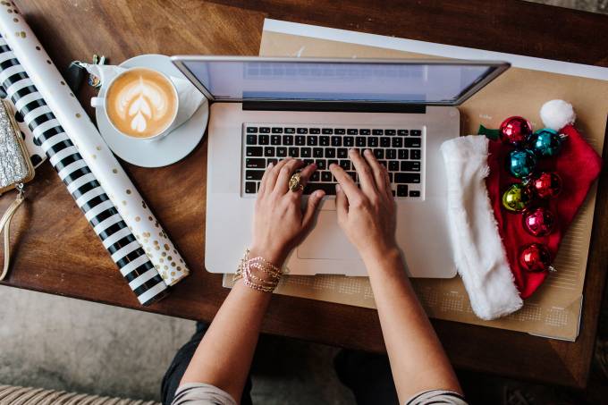 femme utilisant un ordinateur portable avec des articles de Noël sur son bureau.