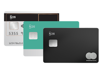 Une rangée de trois cartes de débit N26 Mastercard en argent, sarcelle et noir est étalée sur un fond gris.