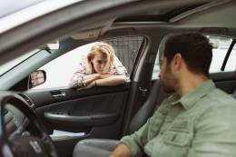 Woman to talks to man in a car.