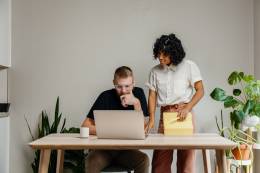 man with a laptop and a woman on his side looking to the laptop.