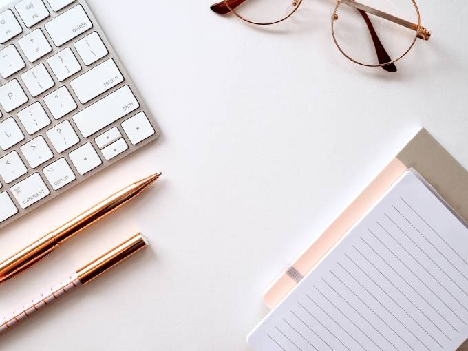 teclado blanco, gafas, lápices y papel.