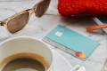 une tasse de café, des lunettes de soleil et une carte bancaire N26 à un café.