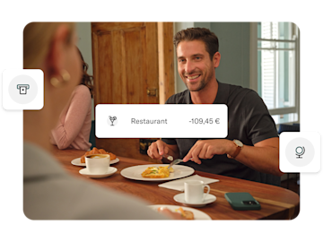 Ein Mann lächelt beim Essen in einem Restaurant, wobei eine Finanztransaktionsbenachrichtigung über „-109,45 €“ für „Restaurant“ über das Bild gelegt ist.