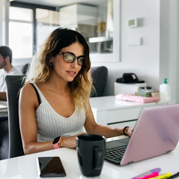 Woman with glasses working from home with a laptop.