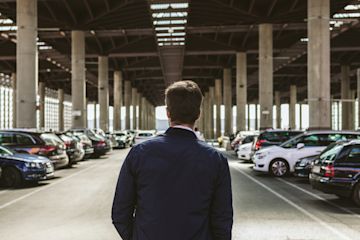 man in a parking with several cars.