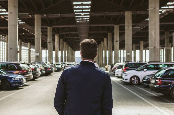 hombre en un estacionamiento con varios coches.