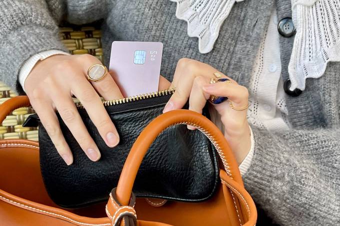 Les mains d'une femme mettant une carte N26 metal dans son porte feuille.