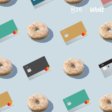 Various N26 debit cards lie next to colorful donuts.