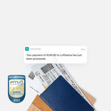 N26 Pushnachricht über Zahlung an eine Fluggesellschaft mit zwei Flugtickets im Hintergrund.