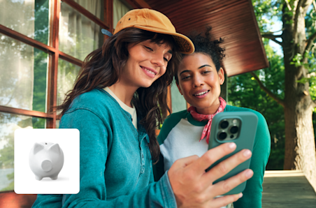 Dos mujeres están una al lado de la otra y miran juntas un teléfono móvil.