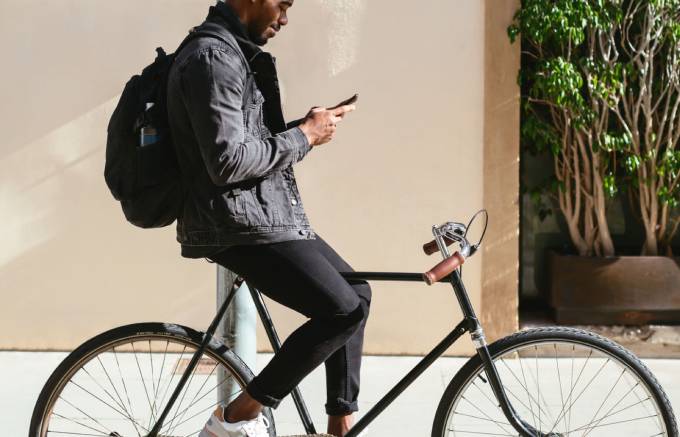 Mann auf Fahrrad mit Handy in den Händen.