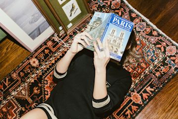 Woman reading travel guide to Paris.