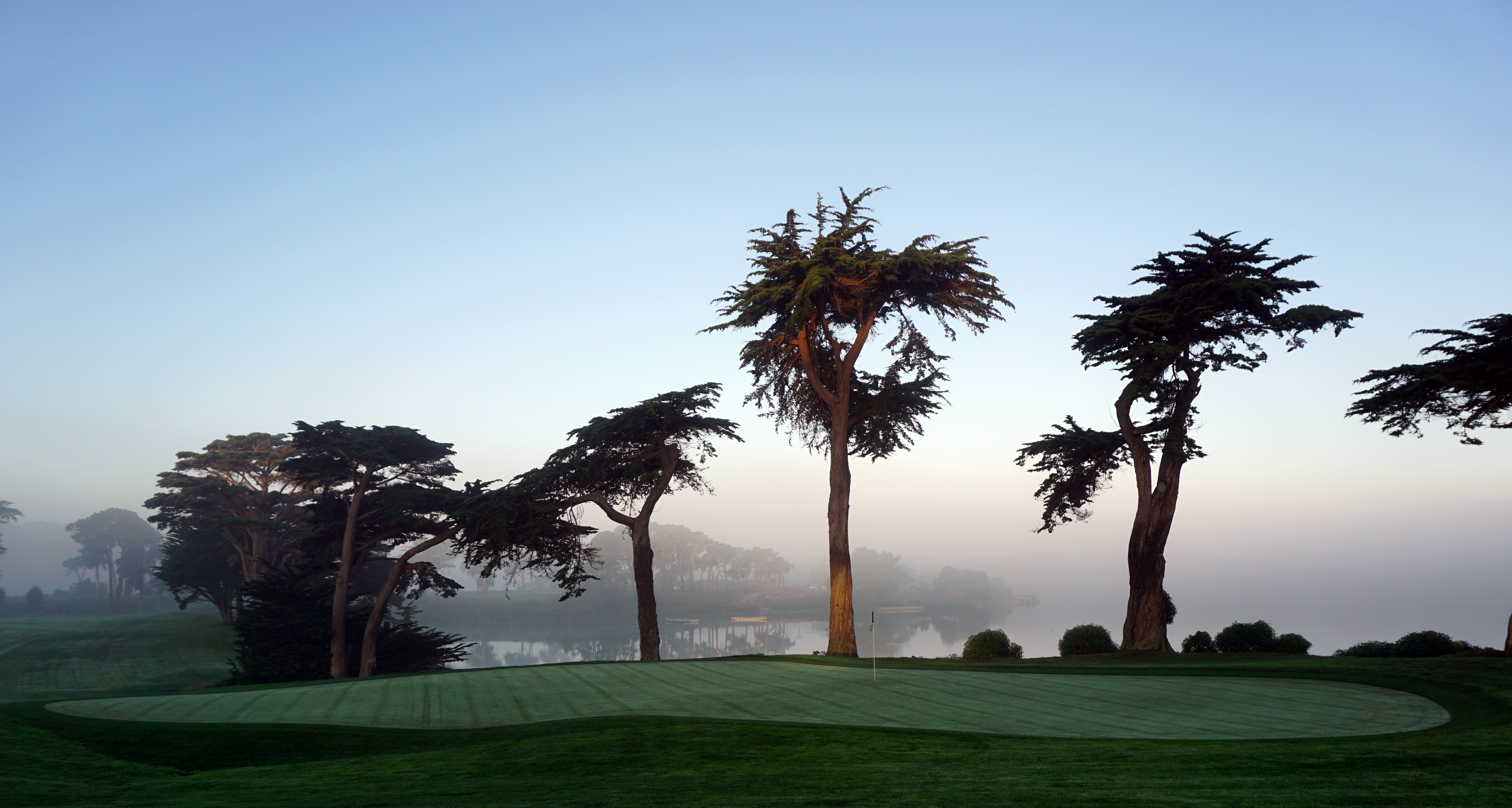 TPC Harding Park's 18th green beside Lake Merced, San Francisco. Photo by Tinou Bao, licensed CC BY 2.0, via Wikimedia Commons: https://commons.wikimedia.org/wiki/File:TPC_Harding_Park_-_18th_Green_(15332936118).jpg