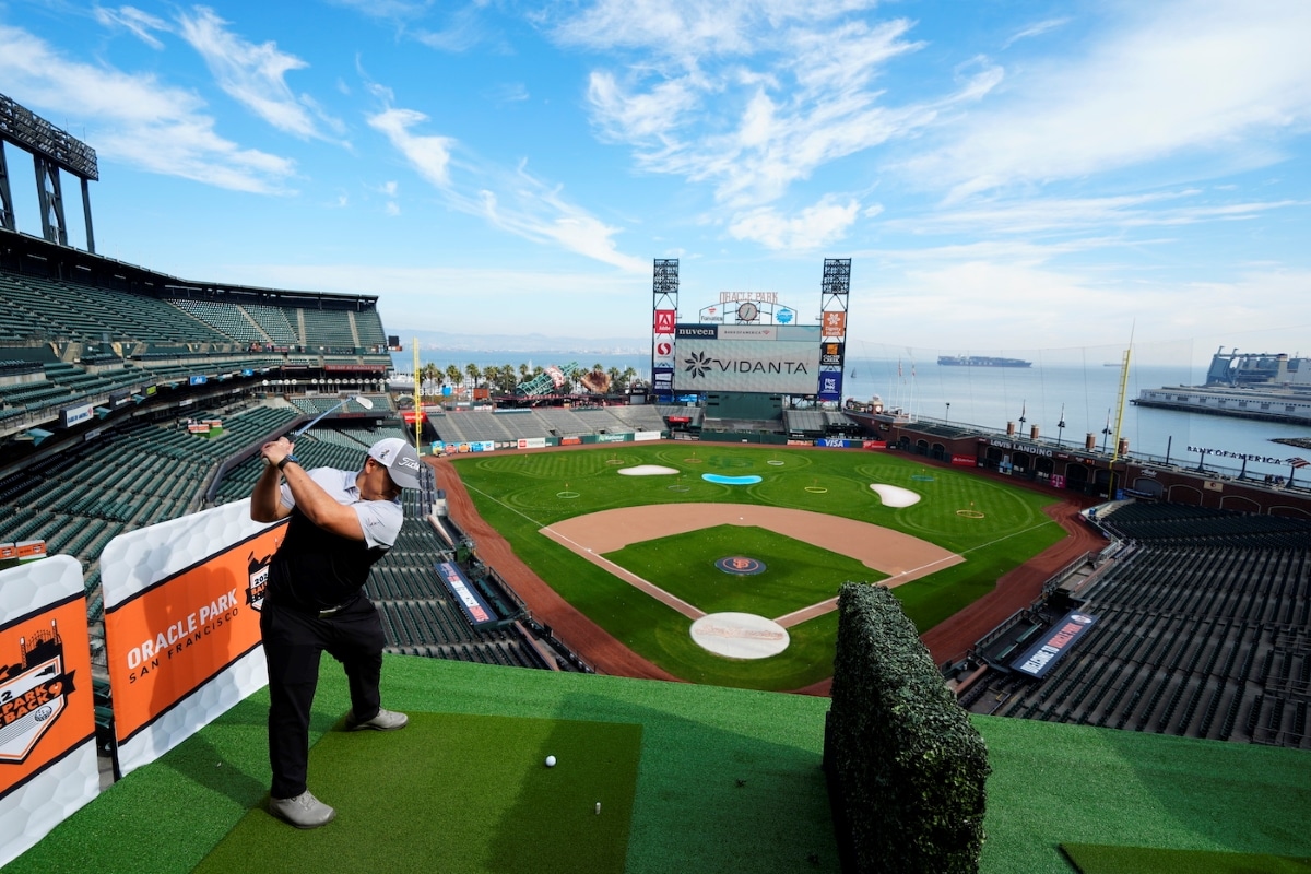 A golfer tees off from the stands toward targets on the field at a previous Ballpark Back 9 event at Oracle Park, with San Francisco Bay beyond. Not the 2026 event setup.