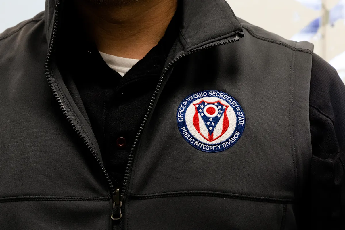 Election Integrity Unit member with a vest showing the Public Integrity shield.