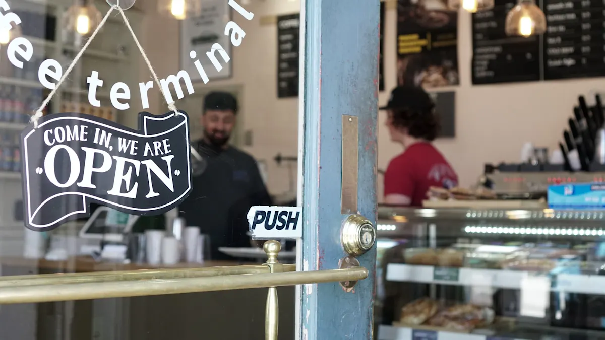 “Open” sign hanging on a café door with staff visible inside behind the counter.
