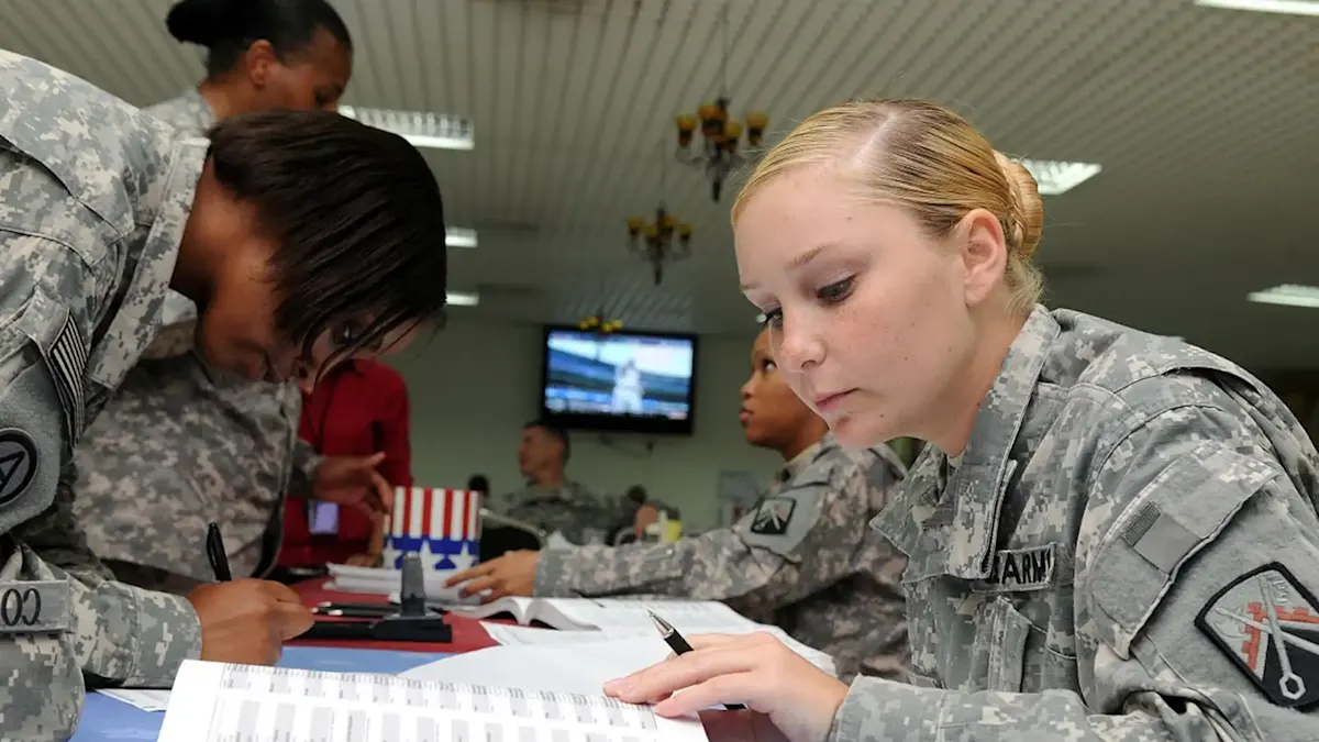 U.S. Army soldiers reviewing and filling out paperwork at a table indoors.