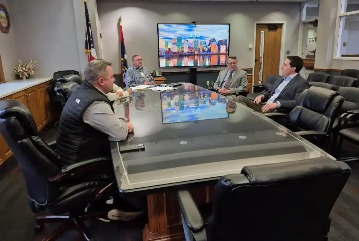Officials seated around a conference table during a meeting in a boardroom.