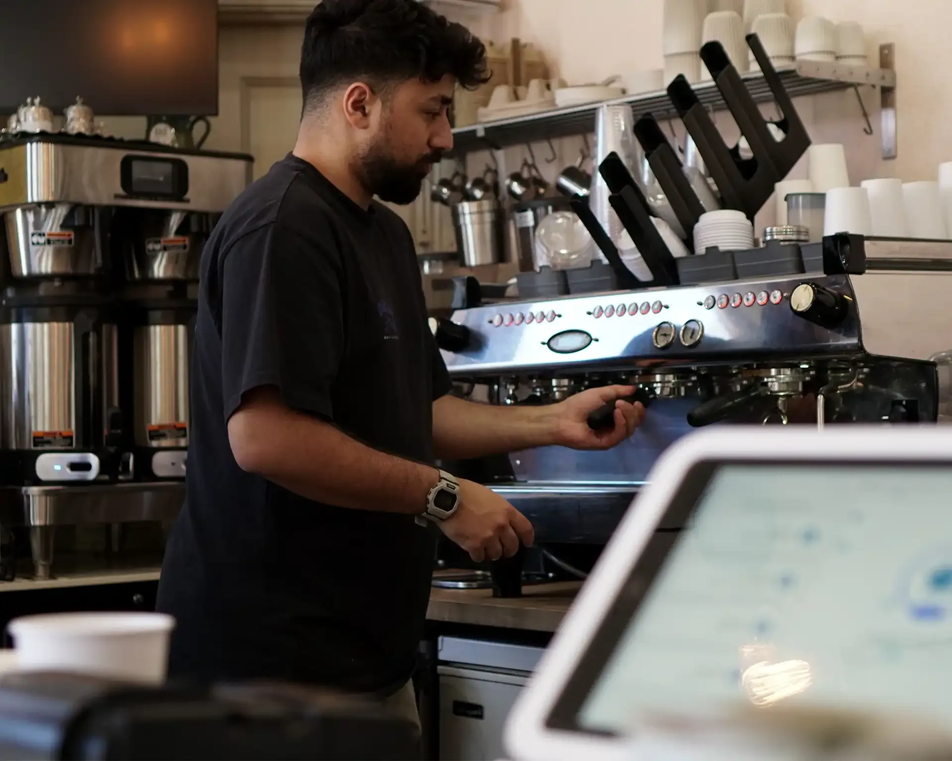 Barista preparing coffee using an espresso machine in a café.