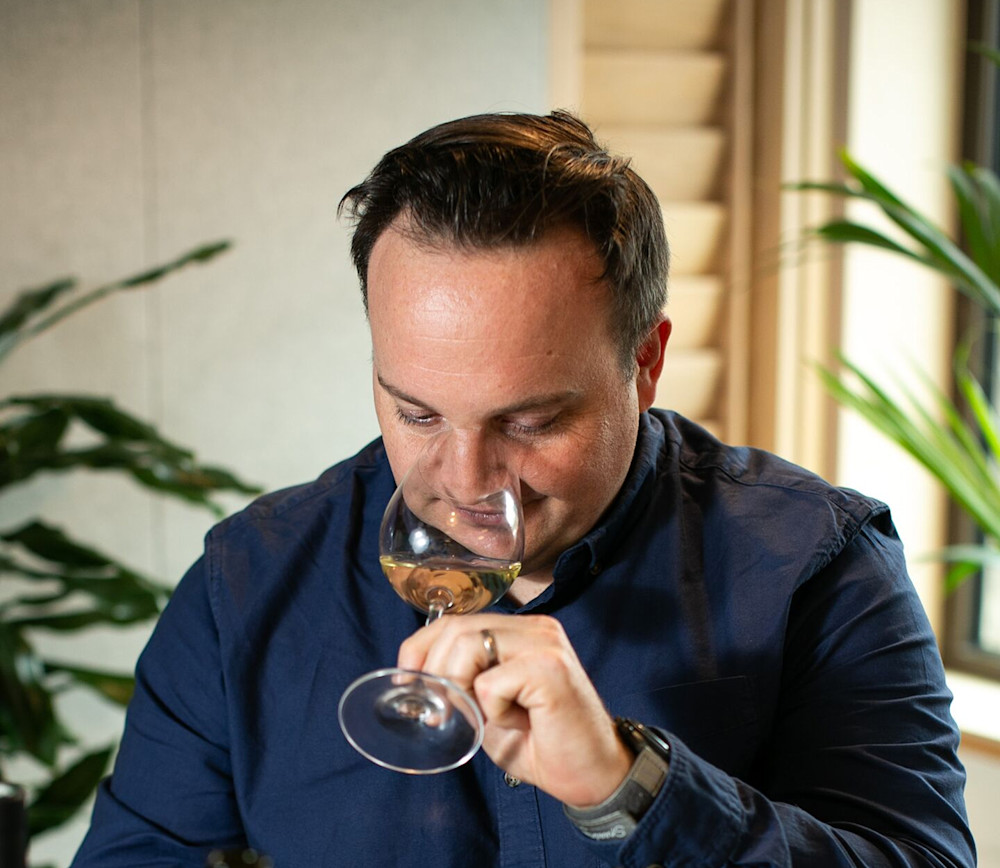 A man smelling white wine in a wine glass