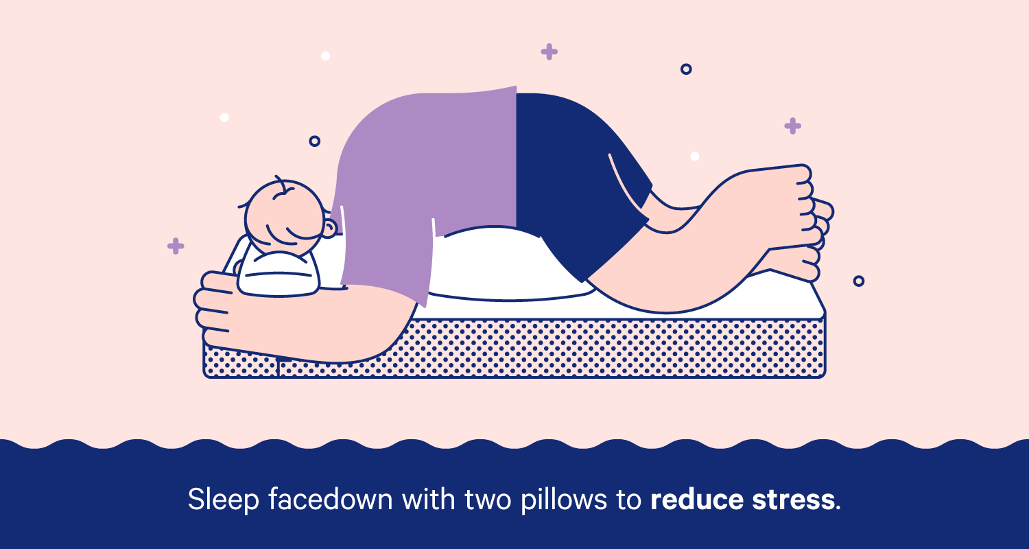 A person sleeping face-down with a pillow under their stomach and a smaller pillow on their forhead.