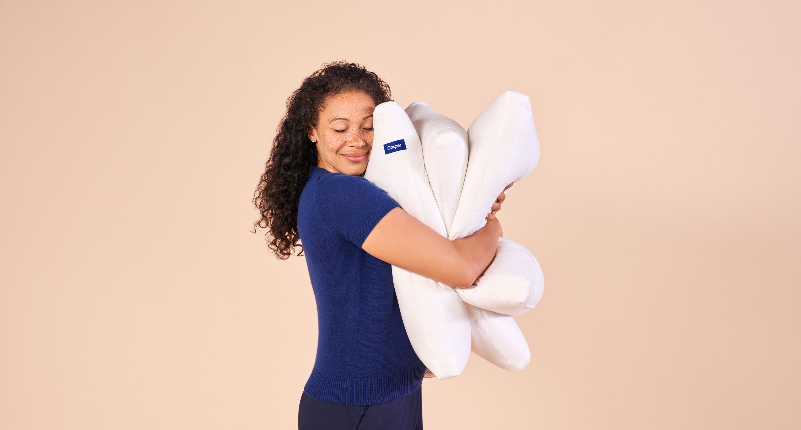 A woman hugs three Casper pillows