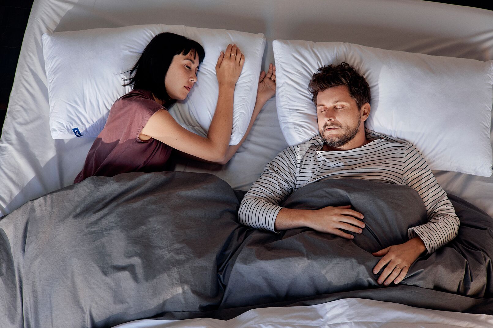 Two partners sleep next to one another on Casper pillows and a Casper mattress.