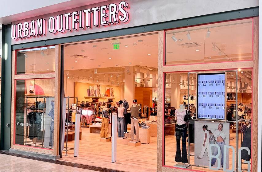 Urban Outfitters store exterior with pink signage and interior view showing colorful clothing displays and folded apparel