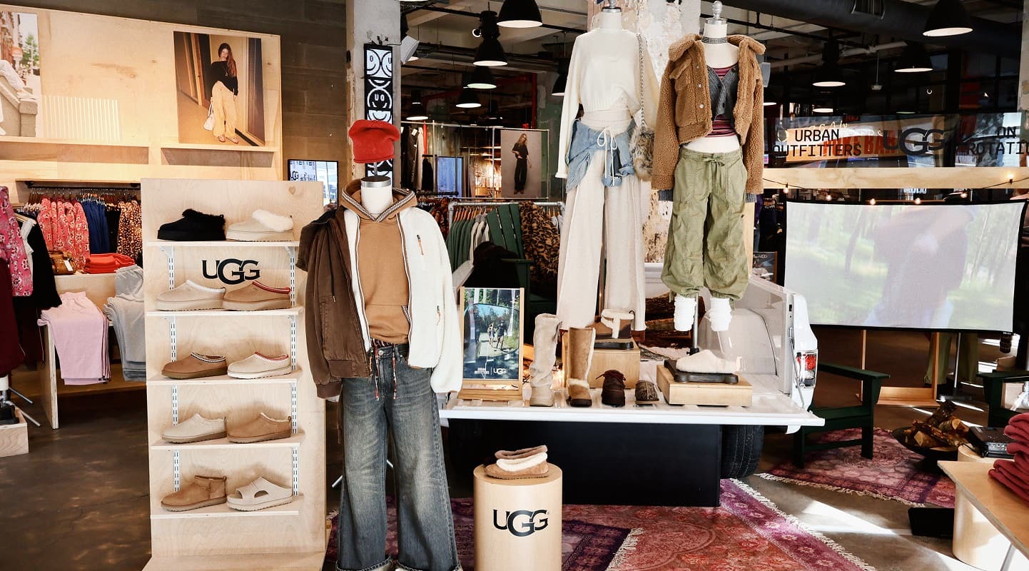 Modern clothing store interior with folded jeans on wooden display table, hanging shirts, and organized shelves with apparel.