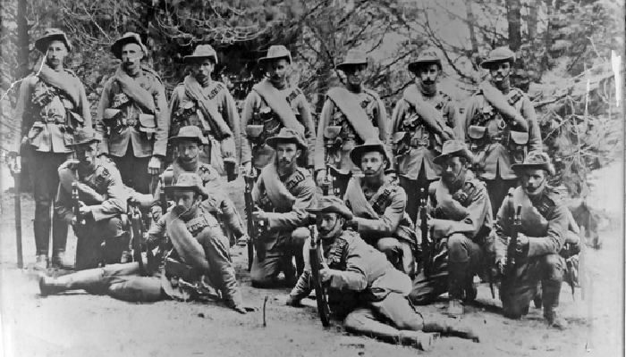 Black and white posed photo of Masterton members of the Fourth Contingent in uniform with guns before they went to the South African War.