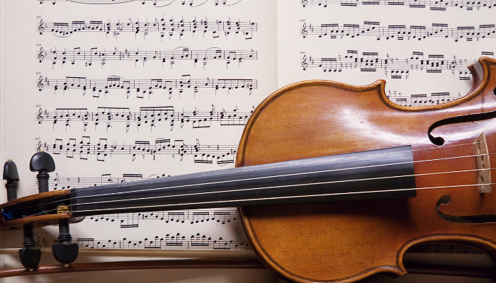 Colour photo showing a close up of a violen in front of some sheet music.