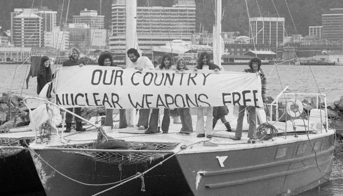 Campaign Against Nuclear Warships (CANWAR) protestors on moored yacht holding banner with words 'Our country nuclear weapons free'.