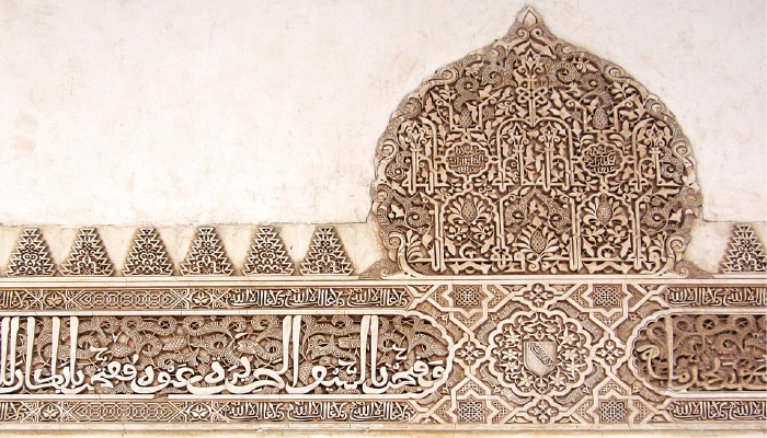 Colour photo of a panel from the Alhambra palace in Granada, Spain, showing intricately carved patterns and Islamic inscriptions.