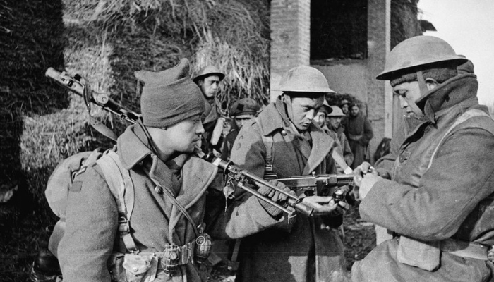 Black-and-white photo showing members of the 28th Māori Battalion checking their weapons.