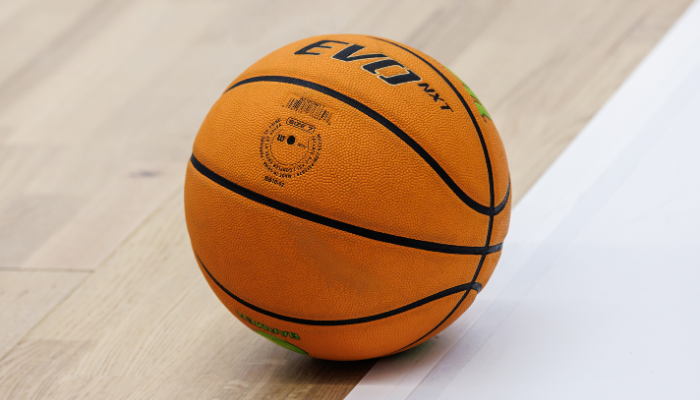 Close up photo of an orange basketball sitting on a basketball court.