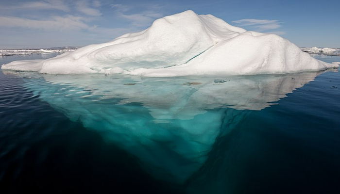 Colour photo of an iceberg floating in water. Shows the iceberg above and below the ocean surface.